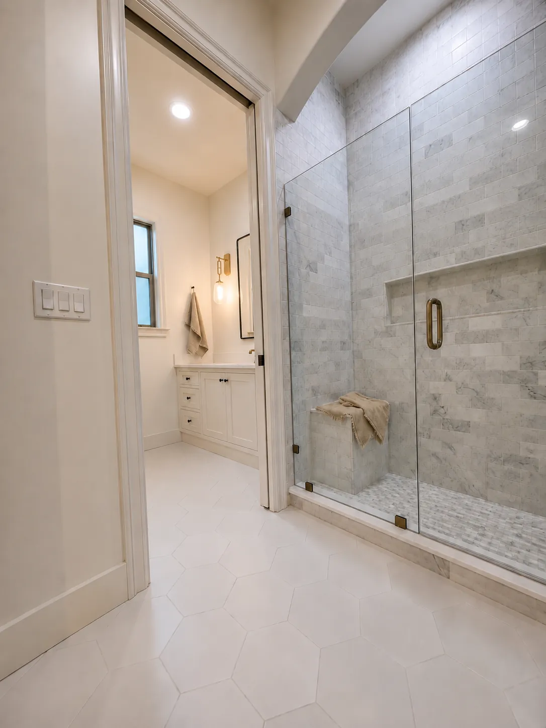 A walk-in marble shower with a bench, next to the vanity.